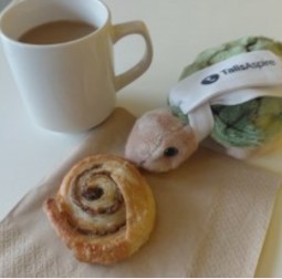 Picture of a mug, danish pastry and a turtle soft toy.